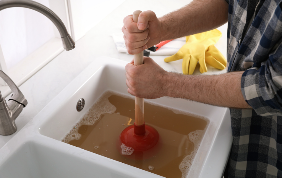 Professional plumber cleaning a blocked kitchen drain using modern equipment.